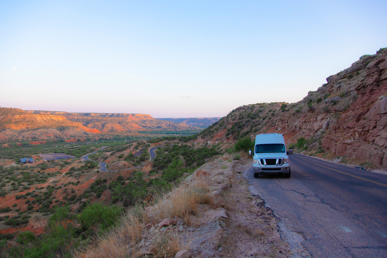 a van cruising the road by the Palo Duro Canyon State Park, with its breathtaking landscapes around in the background